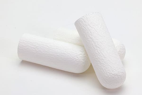 A lab technician holding a cellulose extraction thimble